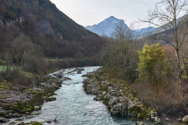 Rio Dobra 'nın, İspanya' nın Asturias kentindeki Olla de San Vicente 'ye giden yürüyüş yolu boyunca yemyeşil bir ormandan akan manzarası. Nehrin berrak suları etrafındaki ağaçları yansıtarak huzurlu ve el değmemiş bir doğal manzara yaratır.. 
