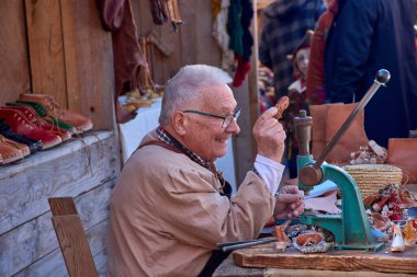 Baiona, Pontevedra, İspanya 2 Mart 2025: Baiona 'daki Arribada Festivali' nde sanatını sergileyen, dönemin kılığına girmiş bir ayakkabıcının büyüleyici bir görüntüsü. 