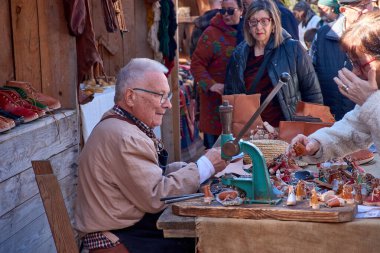 Baiona, Pontevedra, İspanya 2 Mart 2025: Baiona 'daki Arribada Festivali' nde sanatını sergileyen, dönemin kılığına girmiş bir ayakkabıcının büyüleyici bir görüntüsü. 