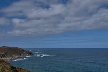 İspanya, Asturias, Faro de San Agustin 'den Cantabrian kıyılarının çarpıcı manzarası. Derin mavi okyanus ufka kadar uzanıyor, yemyeşil bitki örtüsüyle kaplı engebeli uçurumlarla karşılaşıyor.. 