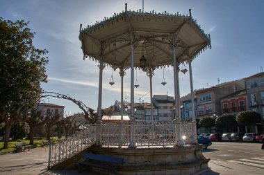 İspanya, Asturias, Vegadeo 'da açık ve güneşli bir gökyüzünün altında büyüleyici bir müzik kulübesi. Büfenin dekoratif tasarımı ve tarihi önemi onu kasaba meydanının odak noktası yapıyor..