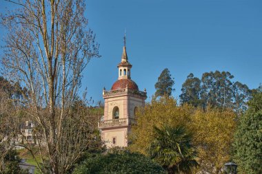 İspanya, Asturias, Vegadeo 'daki Nuestra Senora de La Asuncion Kilisesi' nin çan kulesi güneşli bir gökyüzünün altında. Kulenin detaylı mimarisi ve tarihi önemi vurgulandı. 