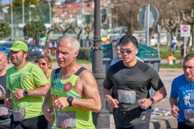 Nigran, Pontevedra, İspanya; 6 Nisan 2025; Bu yakın plan, İspanya 'nın Nigran kentinden geçerken yıllık Vigo-Bayona maratonuna katılan koşucuların enerjilerini ve kararlılıklarını yakalar. Fotoğraf yarışın şiddetini vurguluyor ve...