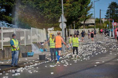 Nigran, Pontevedra, İspanya; 6 Nisan 2025: Yüksek görüşlü yelek giyen genç gönüllüler, İspanya 'nın Nigrn kentindeki Vig Bay Yarı Maratonu sırasında koşuculara suya batırılmış süngerler dağıtıyor. 