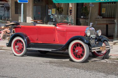 Nigran, Pontevedra, İspanya; 6 Nisan 2025: 1920 'lerin sonlarından kalma canlı kırmızı bir Ford Phaeton, Galiçya' nın Nigrn kentinde güneşli bir caddeye park edilmiştir.. 