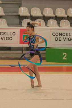 Vigo, Pontevedra, İspanya; 12 Nisan 2025; Ritim jimnastikçisi Vigo, İspanya 'da düzenlenen bir yarışma sırasında kurdele gösterisi yapıyor. Sporcu, yerde dinamik bir hareket gerçekleştirirken tam konsantrasyon içinde yakalanır.. 