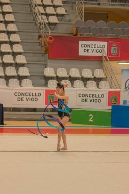 Vigo, Pontevedra, İspanya; 12 Nisan 2025; Ritim jimnastikçisi Vigo, İspanya 'da düzenlenen bir yarışma sırasında kurdele gösterisi yapıyor. Sporcu, yerde dinamik bir hareket gerçekleştirirken tam konsantrasyon içinde yakalanır.. 