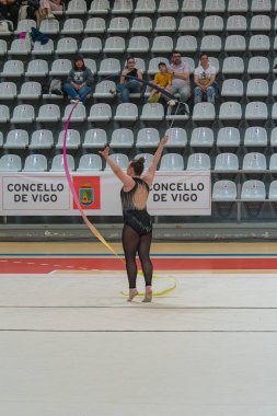 Vigo, Pontevedra, İspanya; 12 Nisan 2025; yetenekli bir jimnastikçi modern Vigo Belediye Spor Salonu 'nda zarif bir şekilde ritmik jimnastik kurdele egzersizleri yapar. Akışkan hareketleri ve kusursuz kontrolü bu disiplinin güzelliğini vurguluyor..