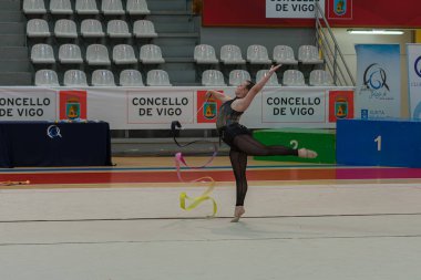 Vigo, Pontevedra, İspanya; 12 Nisan 2025; yetenekli bir jimnastikçi modern Vigo Belediye Spor Salonu 'nda zarif bir şekilde ritmik jimnastik kurdele egzersizleri yapar. Akışkan hareketleri ve kusursuz kontrolü bu disiplinin güzelliğini vurguluyor..