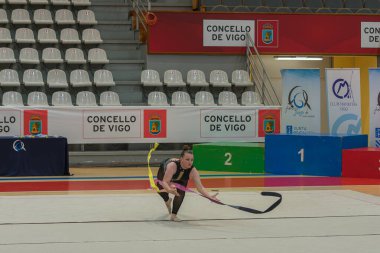Vigo, Pontevedra, İspanya; 12 Nisan 2025; yetenekli bir jimnastikçi modern Vigo Belediye Spor Salonu 'nda zarif bir şekilde ritmik jimnastik kurdele egzersizleri yapar. Akışkan hareketleri ve kusursuz kontrolü bu disiplinin güzelliğini vurguluyor..