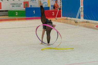Vigo, Pontevedra, İspanya; 12 Nisan 2025; yetenekli bir jimnastikçi modern Vigo Belediye Spor Salonu 'nda zarif bir şekilde ritmik jimnastik kurdele egzersizleri yapar. Akışkan hareketleri ve kusursuz kontrolü bu disiplinin güzelliğini vurguluyor..