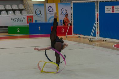 Vigo, Pontevedra, İspanya; 12 Nisan 2025; yetenekli bir jimnastikçi modern Vigo Belediye Spor Salonu 'nda zarif bir şekilde ritmik jimnastik kurdele egzersizleri yapar. Akışkan hareketleri ve kusursuz kontrolü bu disiplinin güzelliğini vurguluyor..