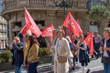 Vigo, Pontevedra, İspanya, 1 Mayıs 2025 'te İspanya' nın Vigo kentinde düzenlenen 1 Mayıs Uluslararası İşçi Bayramı gösterisine büyük bir grup insan katıldı. Kalabalık caddelerde yürürken renkli bayraklar ve afişler görülüyor.