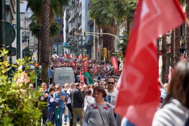 Vigo, Pontevedra, İspanya, 1 Mayıs 2025 'te İspanya' nın Vigo kentinde düzenlenen 1 Mayıs Uluslararası İşçi Bayramı gösterisine büyük bir grup insan katıldı. Kalabalık caddelerde yürürken renkli bayraklar ve afişler görülüyor.