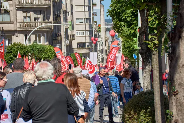 Vigo, Pontevedra, İspanya, 1 Mayıs 2025 'te İspanya' nın Vigo kentinde düzenlenen 1 Mayıs Uluslararası İşçi Bayramı gösterisine büyük bir grup insan katıldı. Kalabalık caddelerde yürürken renkli bayraklar ve afişler görülüyor.