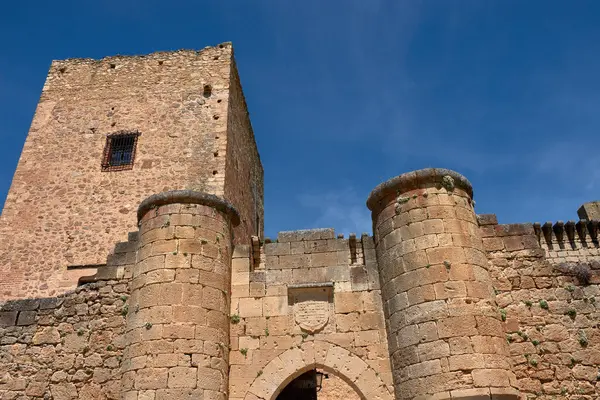 Toprak tonlarda taştan yapılmış Pedraza kalesinin dayanıklı kalesi, duvarların ve dairesel taretlerin bulunduğu açık mavi gökyüzüne karşı görkemli bir şekilde yükselir.. 