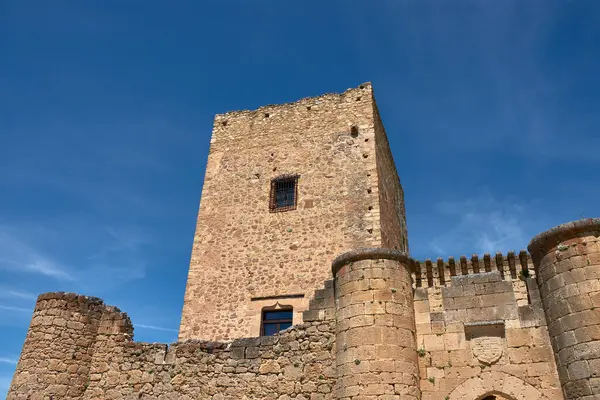 Toprak tonlarda taştan yapılmış Pedraza kalesinin dayanıklı kalesi, duvarların ve dairesel taretlerin bulunduğu açık mavi gökyüzüne karşı görkemli bir şekilde yükselir.. 