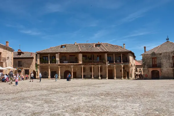 Pedraza, Segovia, İspanya; 24 Mayıs 2025: Pedraza 'nın kaldırım taşlarıyla döşenmiş ikonik Plaza Belediye Başkanı, ahşap balkonlu geleneksel taş evlerle çevrili, açık mavi gökyüzü altında güneşli terasların keyfini çıkaran insanlarla dolup taşıyor.. 