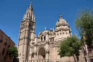 Toledo Katedrali Ayuntamiento Meydanı 'ndan alınan parlak mavi gökyüzünün altında görkemli bir şekilde duruyor. Sıcak taş tonlar, gotik kubbe ve barok kubbe görsel olarak zengin ve tarihsel açıdan önemli bir kompozisyon oluşturur.