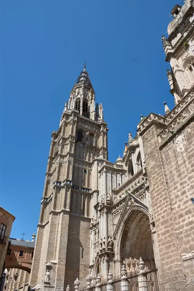 Toledo Katedrali Ayuntamiento Meydanı 'ndan alınan parlak mavi gökyüzünün altında görkemli bir şekilde duruyor. Sıcak taş tonlar, gotik kubbe ve barok kubbe görsel olarak zengin ve tarihsel açıdan önemli bir kompozisyon oluşturur.