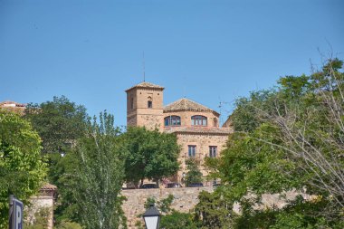 Bölge parlamentosu Cortes de Castilla-La Mancha 'nın tarihi tuğla ve taş binası İspanya' nın Toledo kentinin göbeğinde açık mavi bir gökyüzü altında resmedilmiştir.. 