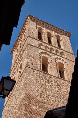 Santo Tome kilisesinin Mudejar tarzı çan kulesi, orta çağ İspanyol mimarisinin tipik karmaşık tuğla ve geometrik desenleri içeren açık mavi gökyüzüne karşı dimdik durmaktadır..