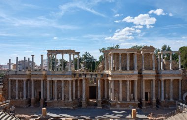 Merida 'daki Roma tiyatrosunun heybetli arkeolojik kalıntıları parçalı bulutlu bir gökyüzü altında sütunlar ve heykellerden oluşan görkemli maskeleriyle sunuluyor.. 