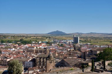 Trujillo 'nun genel manzarası, Caceres, açık ve güneşli bir günde kaleden ele geçirildi. Eski kasaba, arka plandaki kırsal ve dağlık manzarayla çelişen kırmızımsı çatıları, kuleleri ve anıtsal mimarisi ile görülebilir.. 