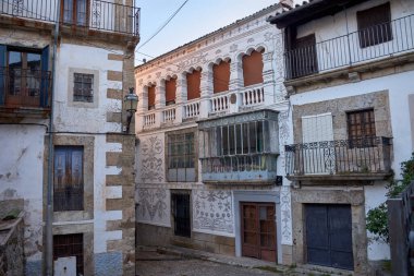 Candelario, Salamanca 'nın pitoresk köyündeki dar bir kaldırım taşı sokak, geleneksel taş evler ve beyaz boyalı duvarlarla çevrili. Çiçek saksıları, huzurlu kırsal alana renk katar.. 