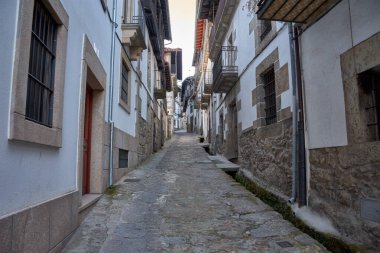 Candelario, Salamanca 'nın pitoresk köyündeki dar bir kaldırım taşı sokak, geleneksel taş evler ve beyaz boyalı duvarlarla çevrili. Çiçek saksıları, huzurlu kırsal alana renk katar.. 
