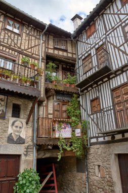 Mogarraz, Salamanca, İspanya; 19 Mayıs 2025: Mogarraz, Salamanca köyünde ahşap balkonları ve taş duvarları olan geleneksel evlerle çevrili bir kaldırım taşı caddesi.. 