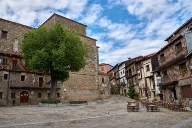 Mogarraz, Salamanca, İspanya; 19 Mayıs 2025: Mogarraz, Salamanca köyünde ahşap balkonları ve taş duvarları olan geleneksel evlerle çevrili bir kaldırım taşı caddesi.. 