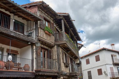 La Alberca 'da balkonları ve pencereleri saksı ve çiçeklerle süslenmiş geleneksel taş ve yarı keresteli evlerle çevrili kaldırımlı bir sokak. Kompozisyon, İspanya 'nın ilk tarihi-sanatsal mekanının kırsal cazibesini ve tarihini vurguluyor.