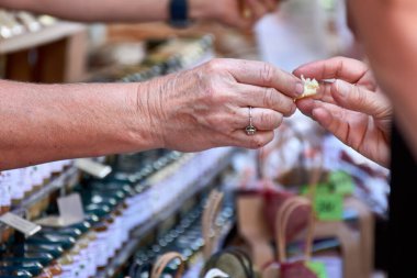 Aix-en-Provence, Fransa 'da bir pazarda el hareketi: bir el, açıkça yüzük takan bir müşterinin, diğer elden, muhtemelen satıcıdan küçük bir parça yiyecek almak üzeredir.. 
