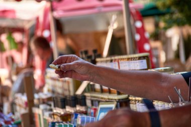Aix-en-Provence, Fransa 'da bir pazarda el hareketi: bir el, açıkça yüzük takan bir müşterinin, diğer elden, muhtemelen satıcıdan küçük bir parça yiyecek almak üzeredir.. 