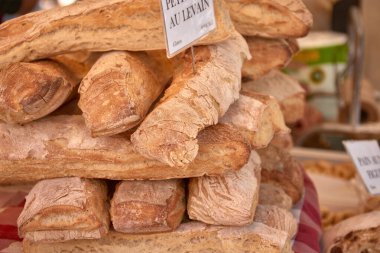 Aix-en-Provence 'da geleneksel bir pazar yerinde, altın kabuklu ve kırsal dokulu somunlar düzenli bir şekilde istiflenerek sıcak ve iştah açıcı bir kompozisyon oluşturulur.. 