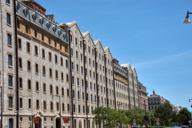 Marsilya 'daki Les Rıhtımı' nın taş cephesi, 19. yüzyıl endüstriyel mimarisinin sağlamlığını ve işlevselliğini çağrıştıran pencerelerin simetrisi ve tekrarı için öne çıkıyor.. 