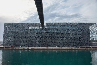 Marsella, Francia, 1 Haziran 2025, Marsilya 'daki Mucem binası, organik desenlerle donatılmış beton kafes, çağdaş tasarımı ve deniz manzarası ile bütünleşmesi açısından göze çarpıyor. Işık ve gölgeler üzerine yansıtılıyor
