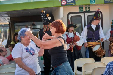Vigo, İspanya, 23 Temmuz 2025, biri genç, biri yaşlı iki kadın, gaydacılar Vigo Estuary 'de bir gemi turu sırasında geleneksel Galiçya müziği çalarken coşkuyla gülüp dans ediyorlar.. 