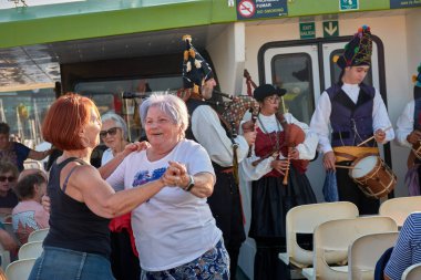 Vigo, İspanya, 23 Temmuz 2025, biri genç, biri yaşlı iki kadın, gaydacılar Vigo Estuary 'de bir gemi turu sırasında geleneksel Galiçya müziği çalarken coşkuyla gülüp dans ediyorlar.. 