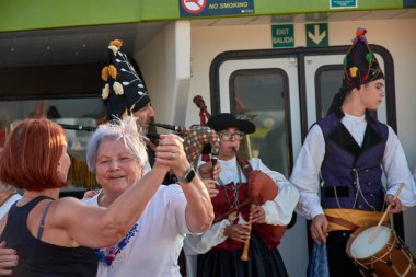 Vigo, İspanya, 23 Temmuz 2025, biri genç, biri yaşlı iki kadın, gaydacılar Vigo Estuary 'de bir gemi turu sırasında geleneksel Galiçya müziği çalarken coşkuyla gülüp dans ediyorlar.. 