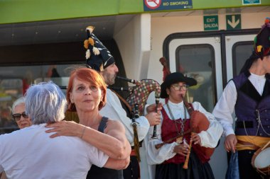 Vigo, İspanya, 23 Temmuz 2025, biri genç, biri yaşlı iki kadın, gaydacılar Vigo Estuary 'de bir gemi turu sırasında geleneksel Galiçya müziği çalarken coşkuyla gülüp dans ediyorlar.. 
