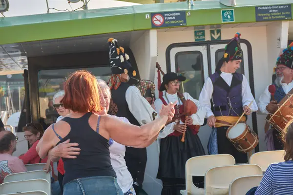 Vigo, İspanya, 23 Temmuz 2025, biri genç, biri yaşlı iki kadın, gaydacılar Vigo Estuary 'de bir gemi turu sırasında geleneksel Galiçya müziği çalarken coşkuyla gülüp dans ediyorlar.. 