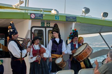 Vigo, İspanya, 23 Temmuz 2025: Geleneksel kostümler giymiş bir grup Galiçyalı müzisyen Vigo Estuary 'nin kalbindeki bir teknede turistlere halk şarkıları söylüyor.. 