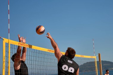 Sabaris, Bayonne, İspanya; 27 Temmuz 2025: Bir plaj voleybol maçında iki oyuncu yoğun bir şekilde karşı karşıya, biri blok yapmaya çalışıyor, diğeri de kollarını kaldırıyor.. 