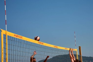Sabaris, Bayonne, İspanya; 27 Temmuz 2025: Bir plaj voleybol maçında iki oyuncu yoğun bir şekilde karşı karşıya, biri blok yapmaya çalışıyor, diğeri de kollarını kaldırıyor.. 