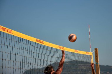 Sabaris, Bayonne, İspanya; 27 Temmuz 2025: Bir plaj voleybol maçında iki oyuncu yoğun bir şekilde karşı karşıya, biri blok yapmaya çalışıyor, diğeri de kollarını kaldırıyor.. 