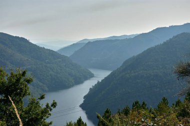 Pesqueiras bakış açısından, Sil Kanyonları yeşil dağlar ve ufku yumuşatan yangınlardan gelen dumanla kaplanmış sakin akan bir nehir arasında açılır.. 