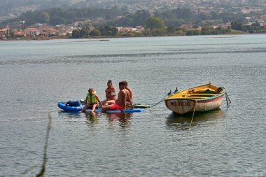 Nigran, Pontevedra, İspanya; 24 Ağustos 2025: Güneşli bir yaz gününde Nigran, Nigran 'da A Foz nehrinde tekne gezisinin keyfini çıkaran bir grup insan. Sahne, doğa ile temasta olan sükunet, aile eğlencesi ve turizmi taşıyor.