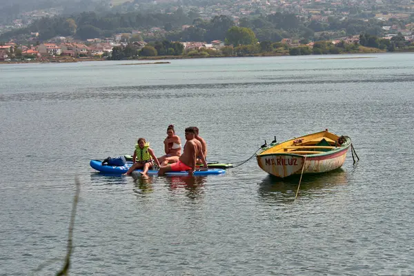 Nigran, Pontevedra, İspanya; 24 Ağustos 2025: Güneşli bir yaz gününde Nigran, Nigran 'da A Foz nehrinde tekne gezisinin keyfini çıkaran bir grup insan. Sahne, doğa ile temasta olan sükunet, aile eğlencesi ve turizmi taşıyor.